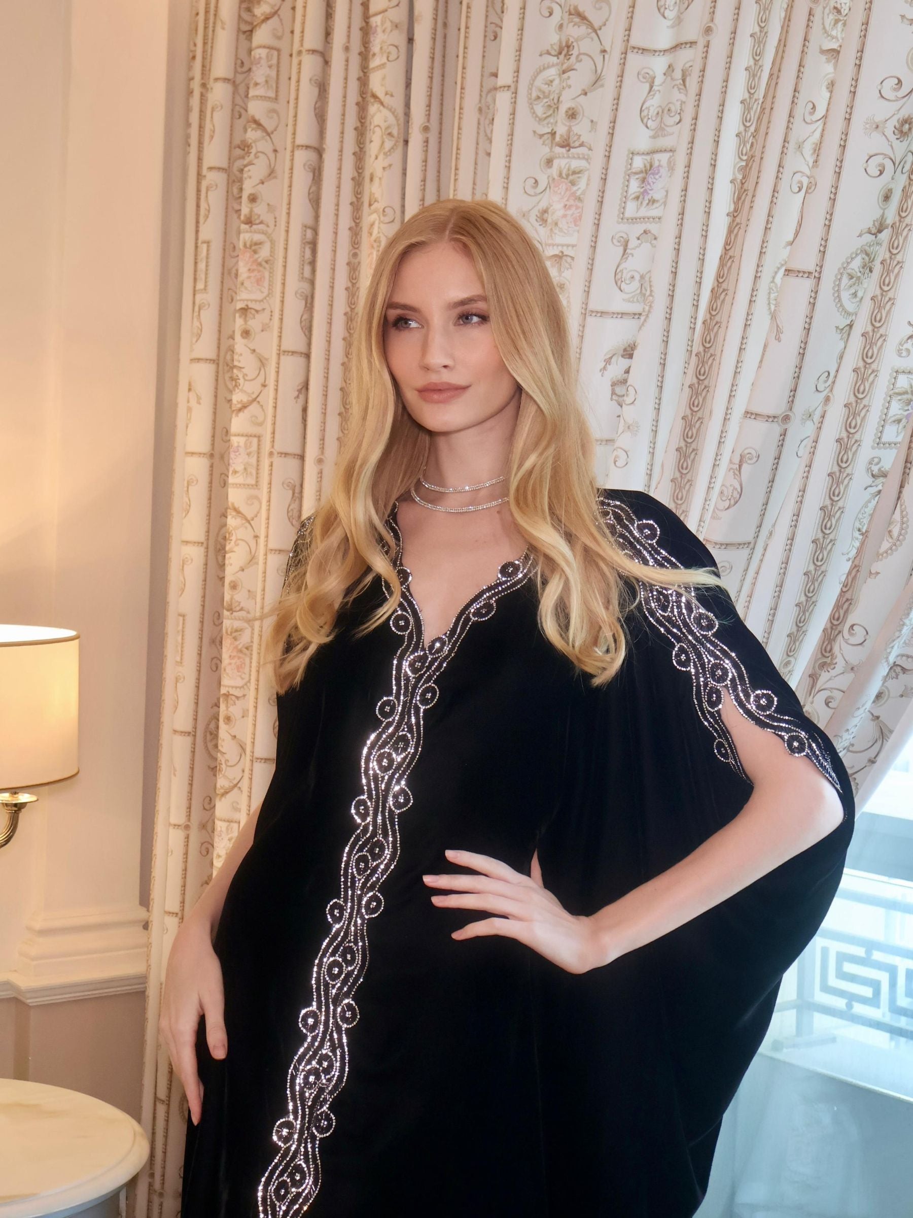 Woman wearing a black dress with white embroidery.