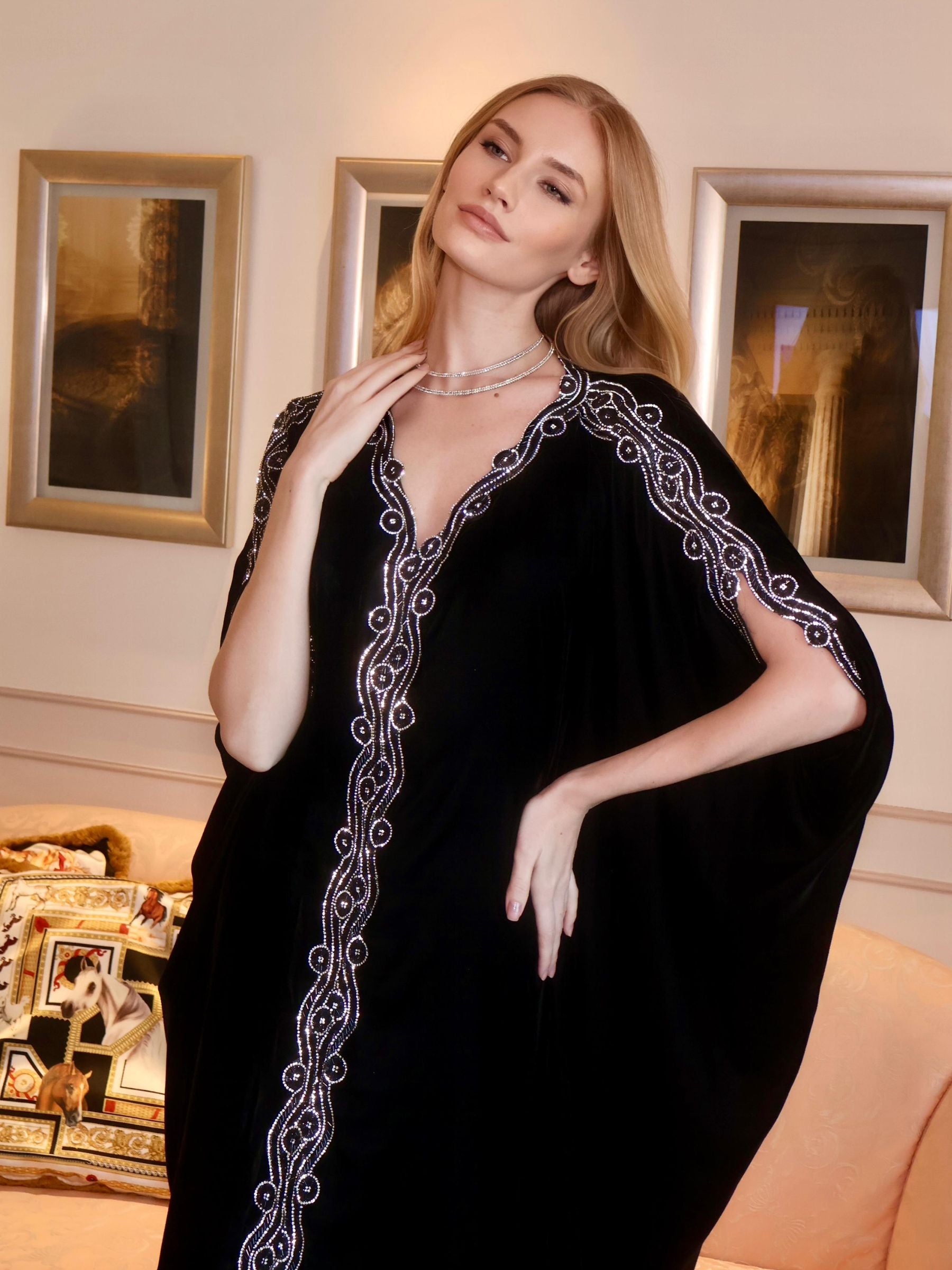 Woman wearing a black dress with white embroidery.